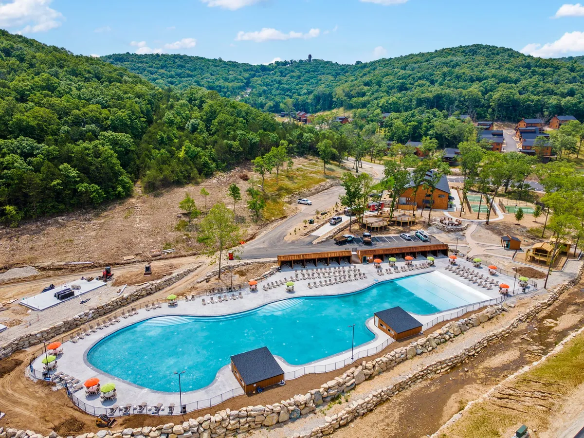 A large outdoor swimming pool is the centerpiece, surrounded by lounge chairs and trees, with designated areas for activities and social gatherings. The pool area appears lively and festive, ideal for summer fun and group activities.